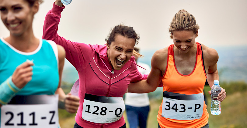Zwei Läuferinnen mit Wasserflaschen in der Hand freuen sich