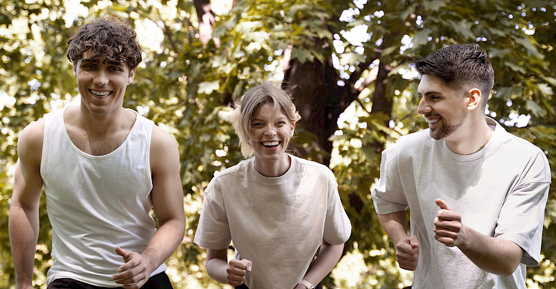 Drei junge Menschen wärmen sich im Wald auf