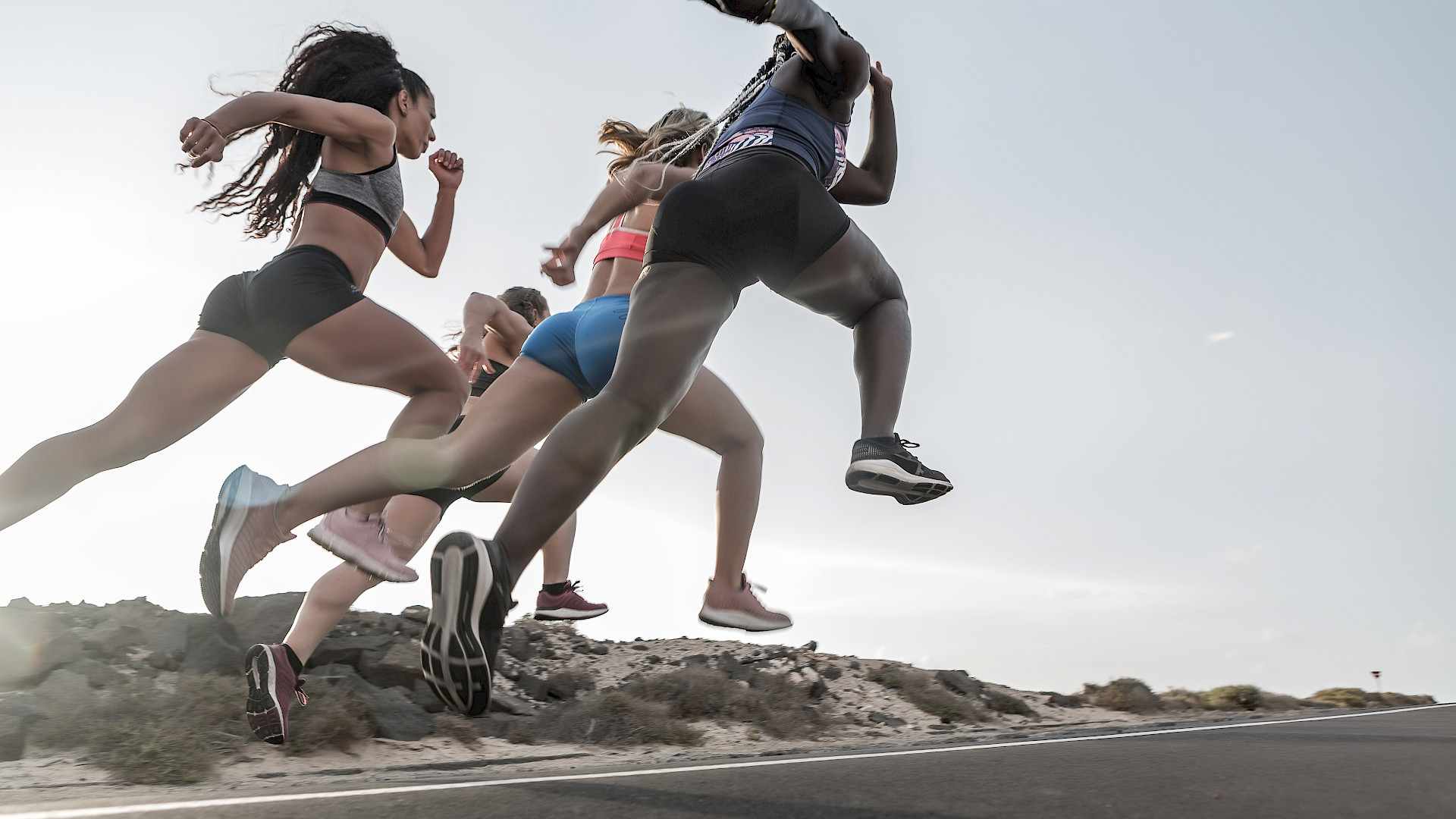 Vier Läuferinnen in Sportkleidung rennen auf einer Straße