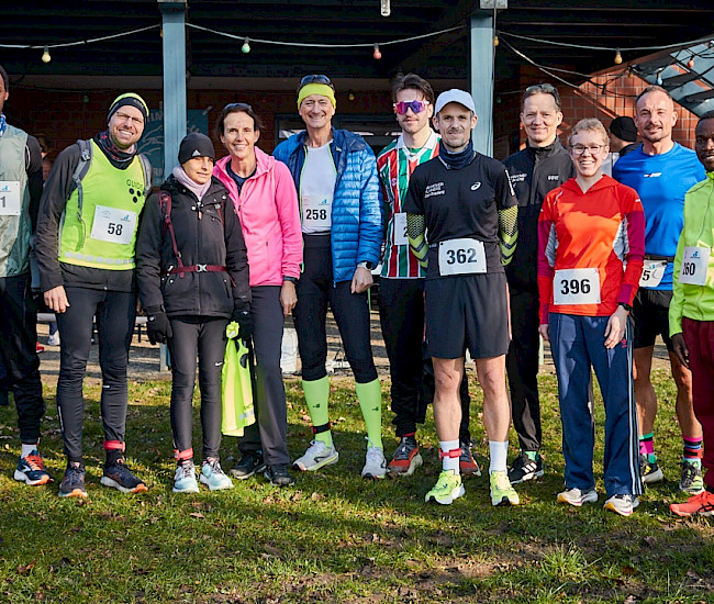 Eine Gruppe von Sportlern mit Startnummern steht auf einer Wiese