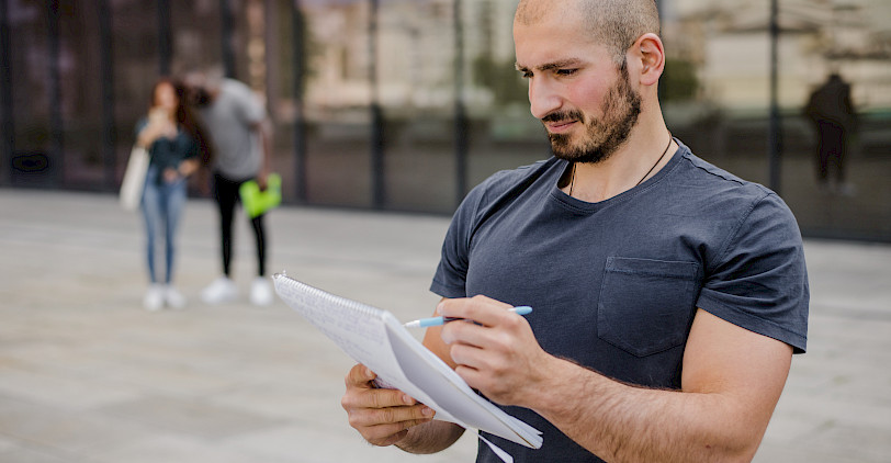 Ein muskulöser Mann füllt im Stehen ein Formular aus