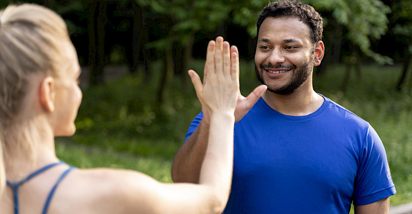 Eine Frau und ein Mann in Sportbekleidung stehen im Wald und schlagen ein