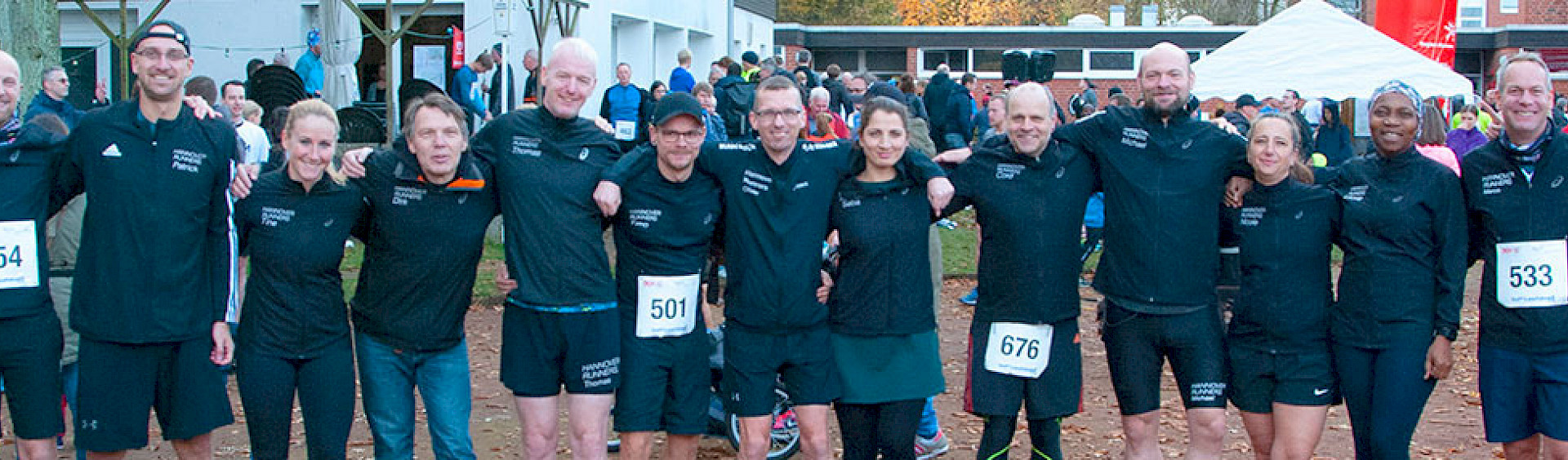 Mitglieder des Teams beim Hannover Runners e.V. stehen Arm in Arm in schwarzer Kleidung