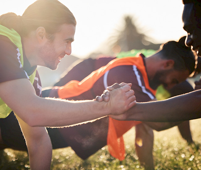 Zwei Sportler wärmen sich mit Liegestützen auf und geben sich gegenseitig die Hand